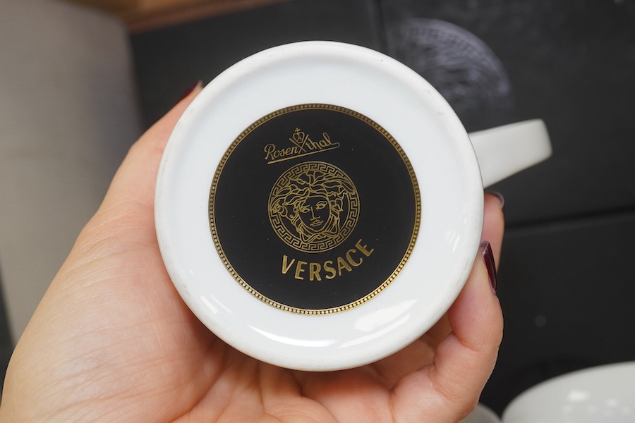 Five boxed Rosenthal for Versace mugs in various colours with Greek key pattern decoration together with a boxed miniature timepiece, 8.5cm high (6). Condition - good.